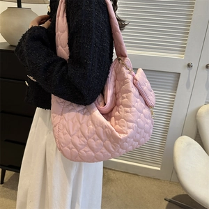 Detail of light pink tote bag featuring heart quilted texture and matching heart coin pouch