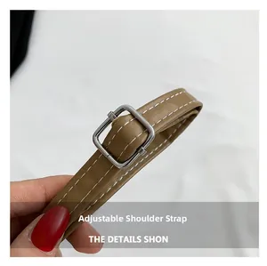 Détail d'une bandoulière réglable en cuir marron avec boucle argentée et surpiqûres