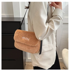 Gros plan sur le mini sac bandoulière en peluche caramel avec broderie sur blazer