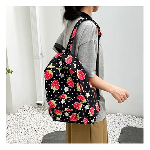 Detail of black strawberry print backpack with vibrant polka dots and zipper pocket
