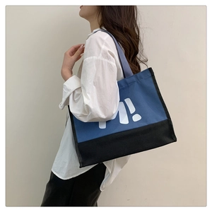 Grand sac cabas en toile avec imprimé lettre M porté par un mannequin en détail