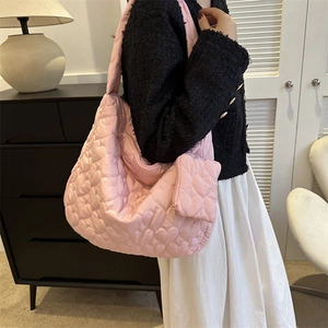 Detailed close-up of pink heart-quilted hobo bag with matching mini heart coin purse