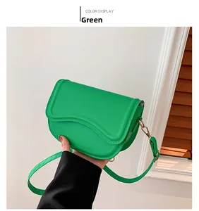 Detail view of green leather saddle bag with wave-shaped flap and gold metal hardware