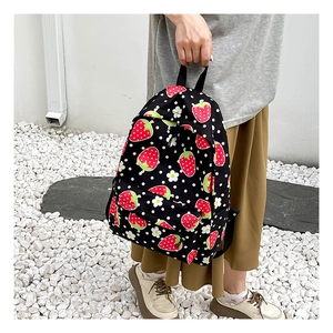 Detail of waterproof nylon backpack featuring red strawberry and white daisy prints