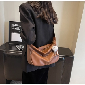 Détail du sac croissant en cuir marron grainé avec un porte-clés en peluche mignon