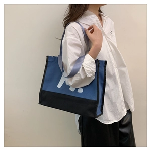 Détail du cabas en toile bleu et noir avec larges anses en nylon et imprimé lettre M