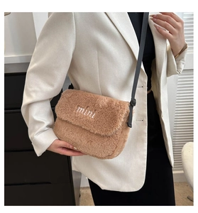 Détail du sac bandoulière en peluche marron avec broderie mini porté par un mannequin