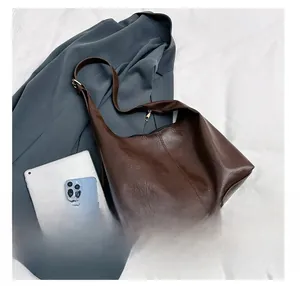 Detail presentation showing dark brown leather tote capacity with iPad and smartphone