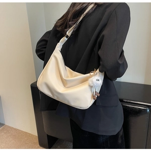 Détail du sac hobo en cuir grainé blanc cassé avec une breloque peluche monstre