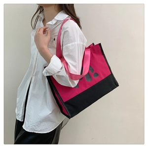 Détail du sac cabas en toile fuchsia et noir avec lettrage porté par un mannequin