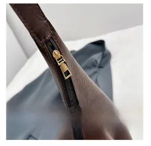 Close-up of smooth gold metal zipper on premium brown lychee pattern leather tote bag