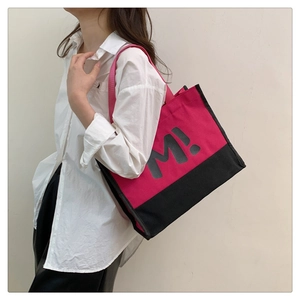 Détail du cabas en toile fuchsia et noir avec imprimé M! porté par un mannequin