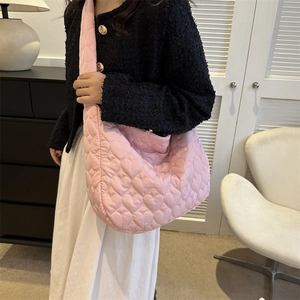 Detailed view of the pink heart-quilted puffer tote bag worn over a shoulder