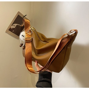 Détail du sac hobo en cuir marron avec bandoulière en nylon et breloque peluche