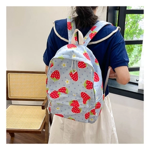 Detail of light blue strawberry canvas backpack with white daisy prints on model