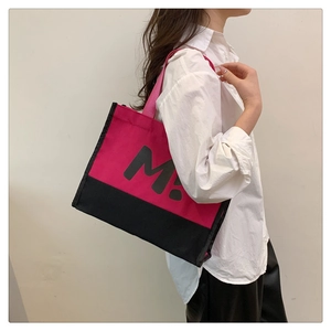 Détail du grand sac cabas en toile montrant le contraste rose et noir et l'imprimé M
