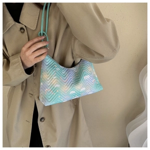Detail of macaron gradient underarm bag with zigzag quilting and braided strap on a model