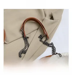 Detail of adjustable chain strap with faux fur trim on a brown leather shoulder bag