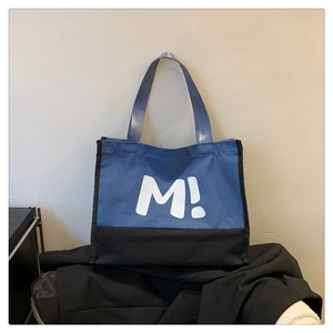 Détail du sac cabas en toile bleu et noir avec une lettre M blanche imprimée dessus