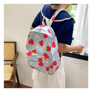 Detail view of light blue backpack featuring red strawberry and white daisy patterns