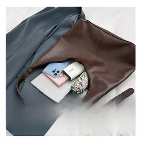Detail presentation of large brown hobo bag showing spacious interior with tablet and umbrella