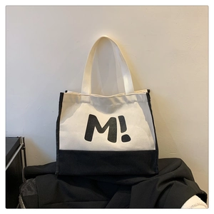 Gros plan sur le grand sac cabas en toile avec imprimé lettre M et fond noir