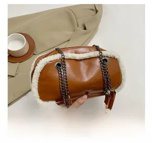 Detail of brown faux leather handbag with white faux fur trim and gold chain strap