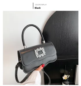 Détail du sac rétro noir avec des surpiqûres blanches et une boucle en cristal brillant