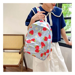 Detailed view of the strawberry print pattern and fabric texture on a blue school backpack