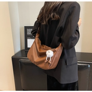 Détail du sac hobo en cuir marron caramel avec grain naturel et breloque pelucheuse
