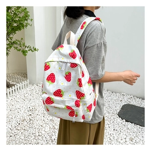 Lifestyle view of strawberry print backpack showing straps and side profile on a model