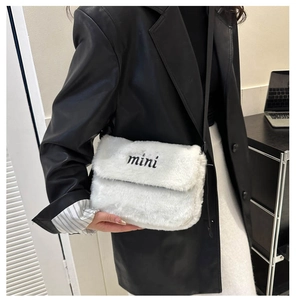 Détail d'un sac bandoulière en peluche blanche avec broderie mini noire et fine lanière