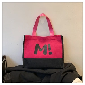 Détail du sac cabas en toile bicolore avec imprimé lettre M et poignées en sangle rose