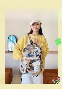 Detail of trendy camouflage school backpack with fashion logo and teddy bear charm