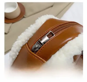 Detail shot of smooth metal zipper on brown leather bag with white faux fur trim