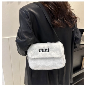 Détail du mini sac bandoulière en peluche blanche avec broderie sur veste en cuir