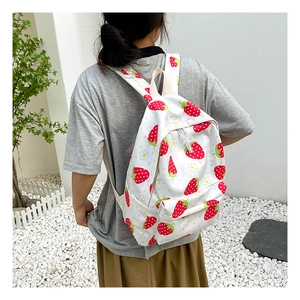 Detail of white backpack with strawberry and daisy prints on adjustable straps and pockets