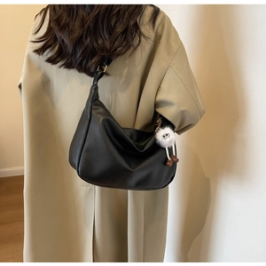 Détail du sac hobo en cuir grainé noir avec charm monstre mignon sur la bandoulière