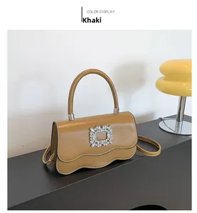 Détail du sac kaki aux bords ondulés avec une boucle carrée ornée de cristaux brillants