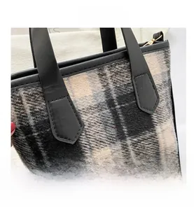 Close-up of black and yellow plaid tweed fabric texture and durable leather handles