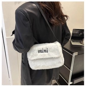 Détail du sac à bandoulière en peluche blanche avec broderie mini et sangle noire sur mannequin