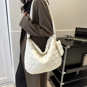 Detail view of large white quilted tote bag with heart embroidery on model in office