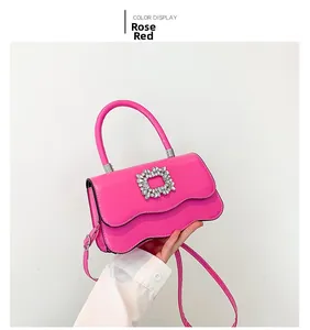 Détail du sac fuchsia en cuir avec bord ondulé et boucle carrée incrustée de cristaux