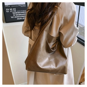 Detailed view of the dark brown oil-wax leather tote bag on model's shoulder