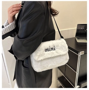 Détail d'un sac bandoulière en peluche blanche avec broderie mini et lanière