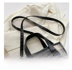Close-up of adjustable leather shoulder strap with gold buckle on plaid tote bag