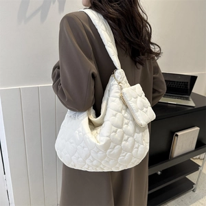 Detail of white quilted tote bag with heart patterns and small attached accessory pouch