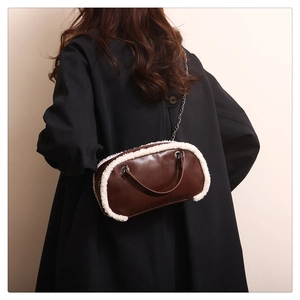 Detail of brown leather crossbody bag with white faux fur trim and silver chain strap