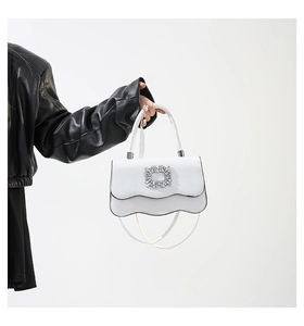 Détail du sac à main blanc avec rabat festonné et grande boucle carrée en cristal