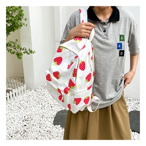 Detail of white strawberry pattern backpack with canvas texture and red strawberry prints